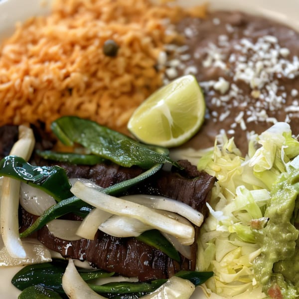Serranos Mexican Grill's carne asada with grilled onions, peppers, rice, beans, guacamole, and lime.