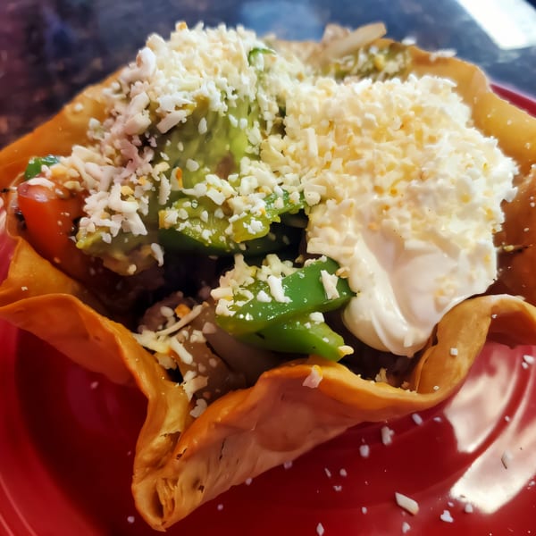 A Serranos Mexican Grill taco salad in a crispy tortilla bowl with sour cream and cheese.